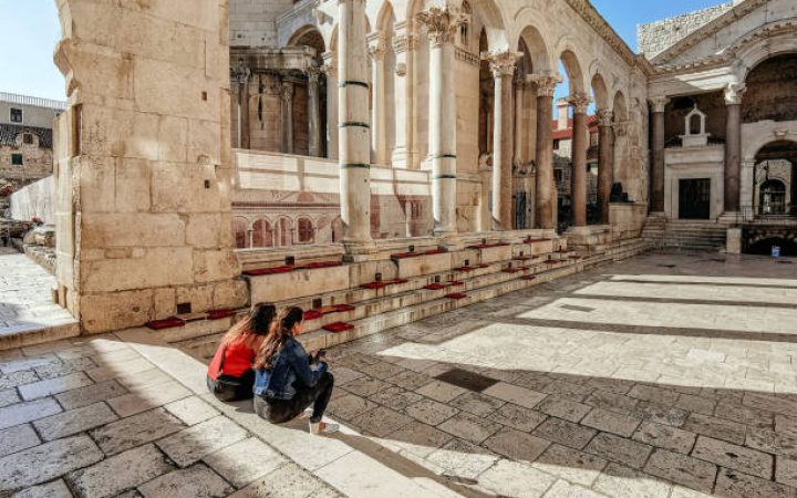 Two friends sitting on steps of Peristyle or Peristil of ancient roman palace built by emperor Diocletian in Split, Croatia.
